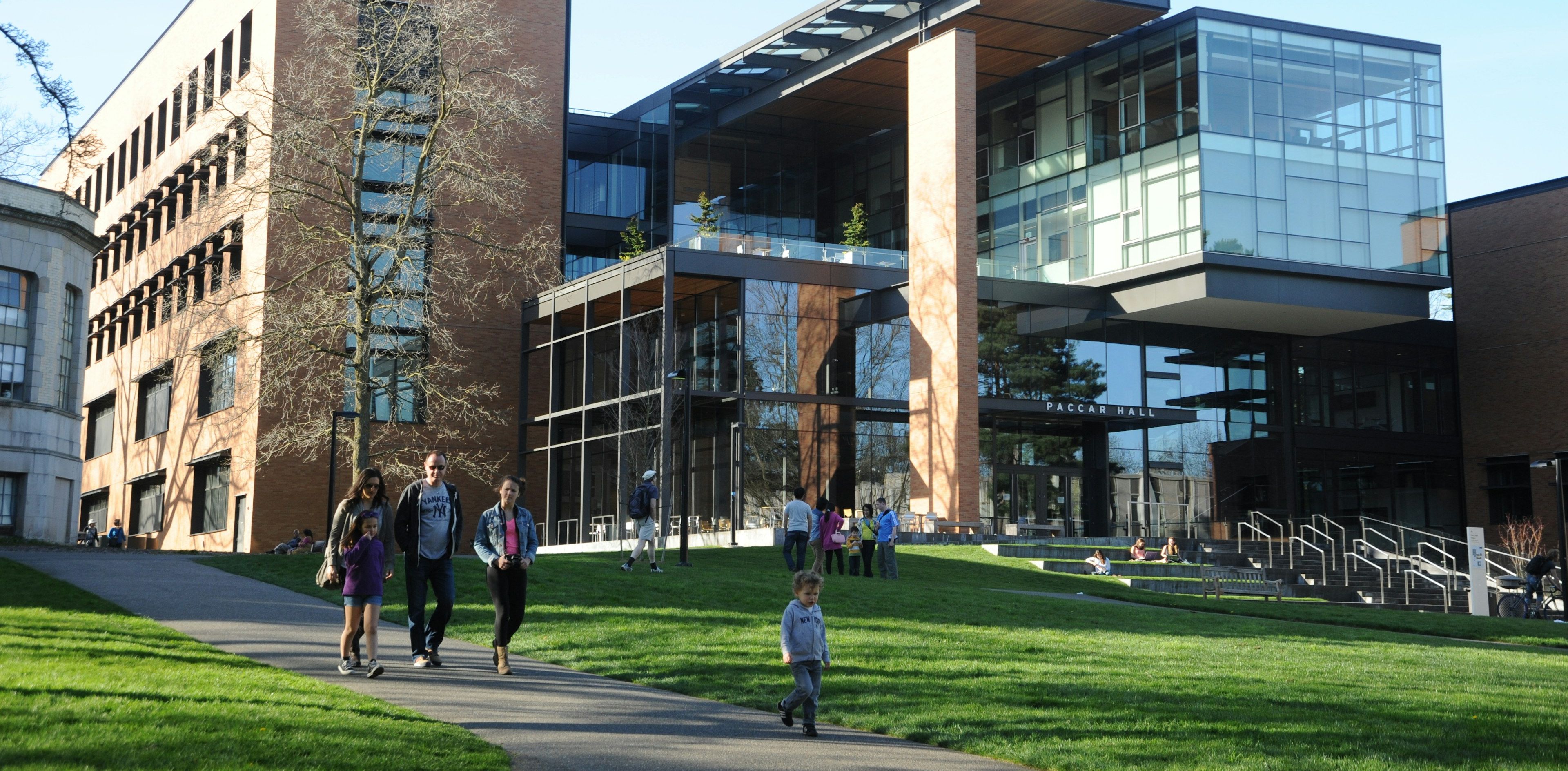 Students walking past Paccar Hall on a university campus in the late-afternoon sun